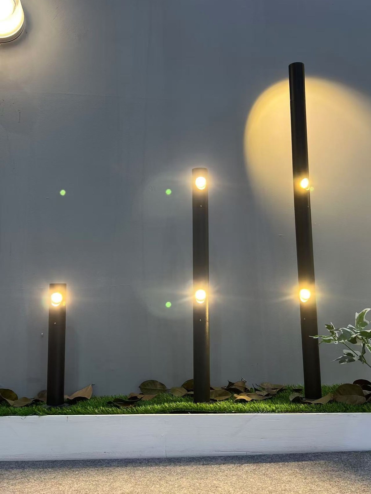 Bollards in close-up — three heights lighting the turf